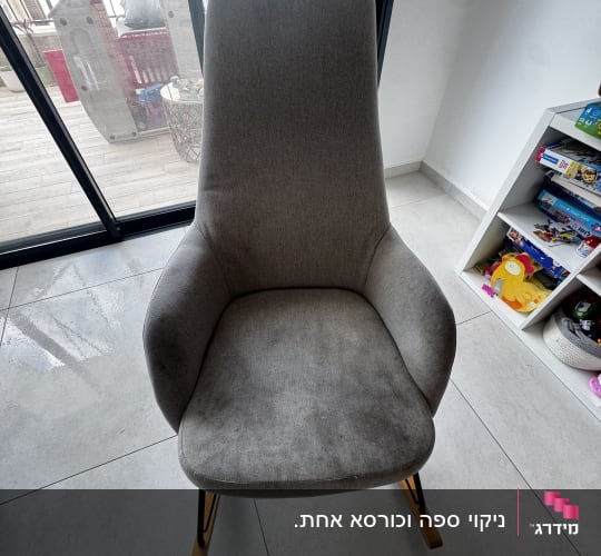 כיסא אפור ליד חלון עם צעצועים ברקע